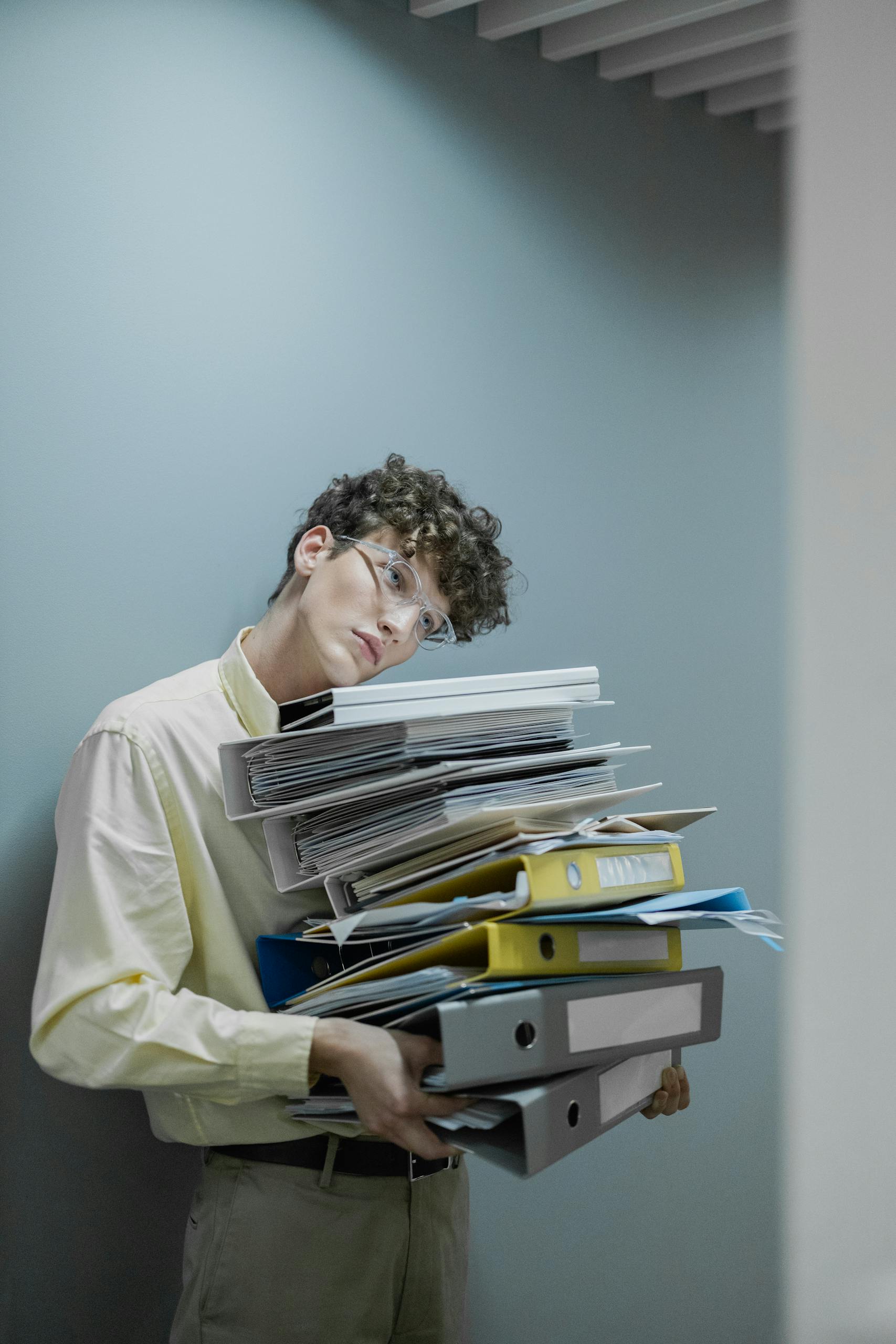 Person in Yellow Long Sleeve Shirt Carrying Stack of Office Files